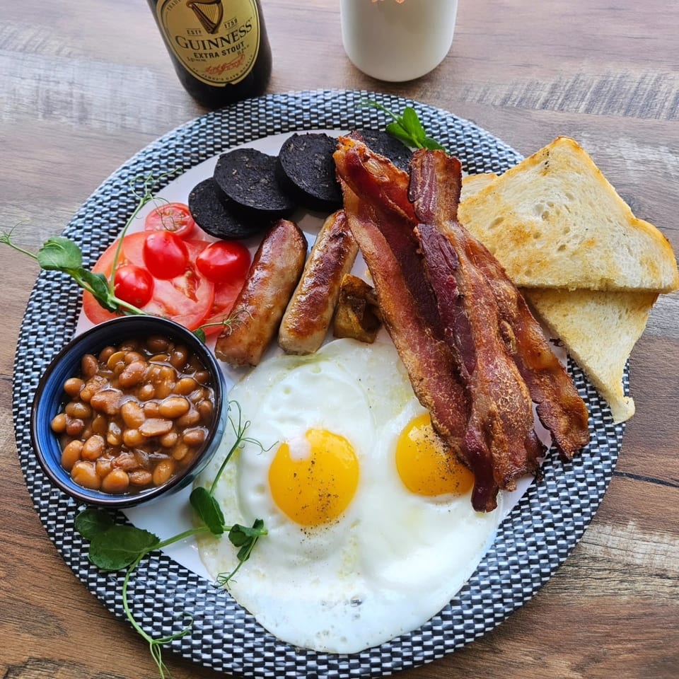A full Irish breakfast with eggs, bacon, sausages, black pudding, beans, tomatoes, and toast.