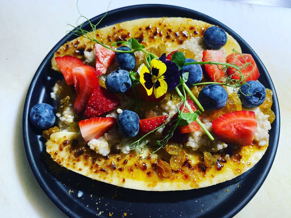 Banana split with oatmeal, blueberries, strawberries, golden raisins, and edible flowers.